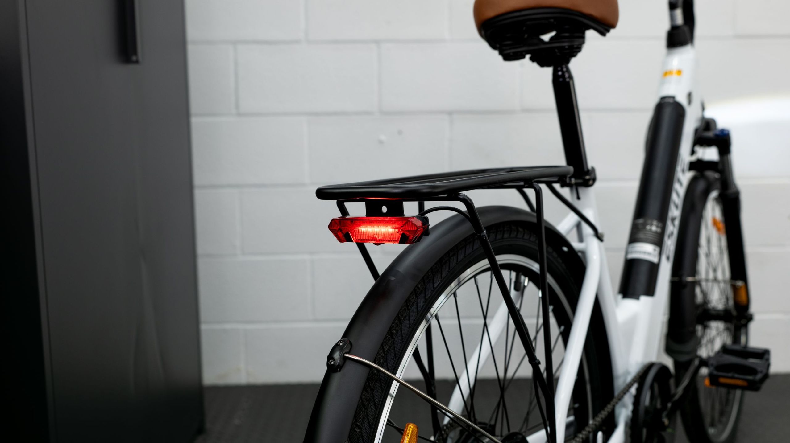 the rear of a white ebike with a rack, a taillight and and fender