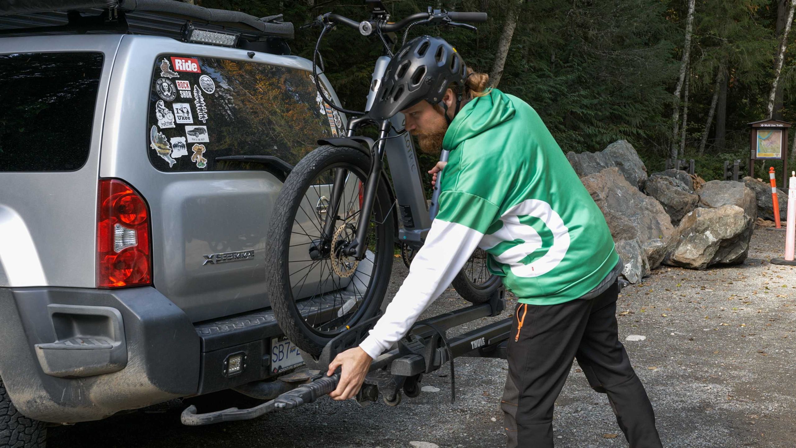 man in a green hoodie attaching a bike to a hitch rack