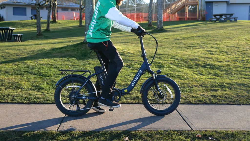 man in green hoodie riding a folding bike on pavement