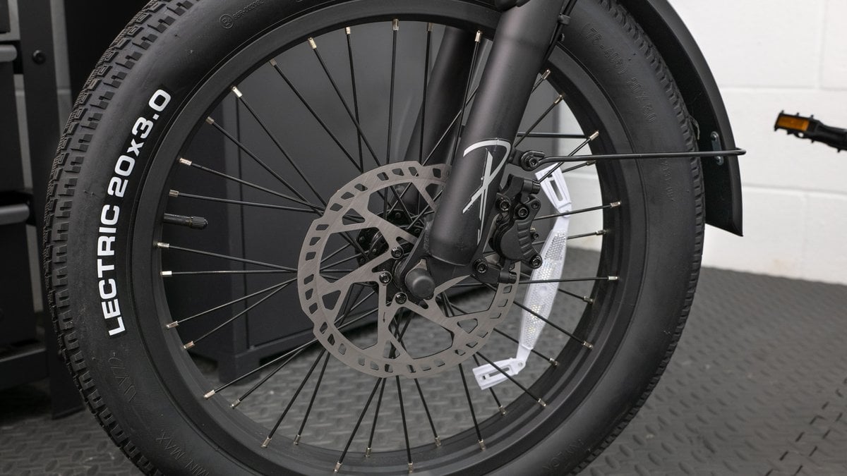 A front disc brake caliper and rotor on a test bike, checked for alignment after assembly